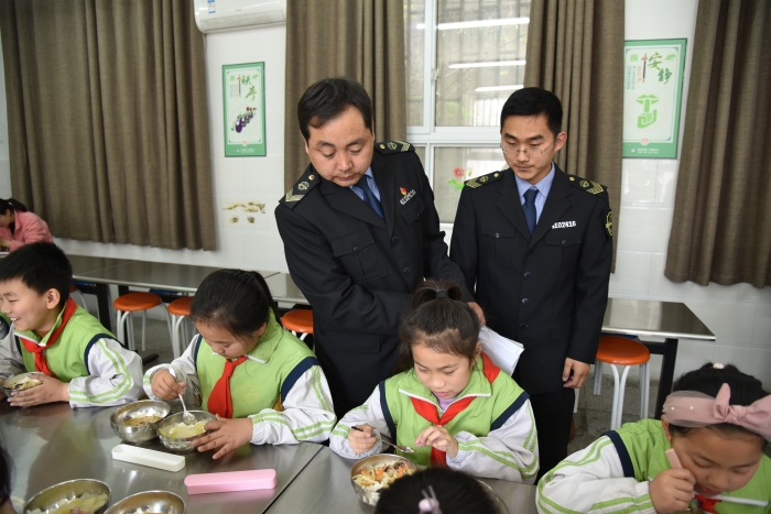 图为执法人员检查食堂食品安全情况。