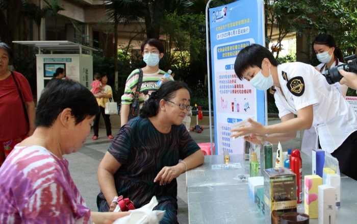 图为检验人员在为群众现场讲解辨别假冒伪劣化妆品的方法。（程奇 摄）