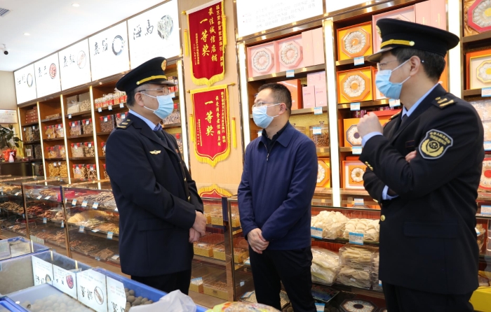 秦继红（左一）在中药材市场听取长沙市、雨花区市场监管局负责人介绍相关情况。（喻灿华 摄）