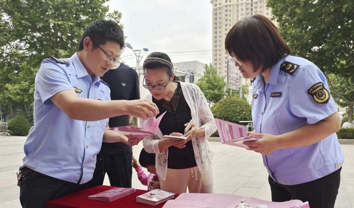 图为该局工作人员向群众发放化妆品科普宣传资料。